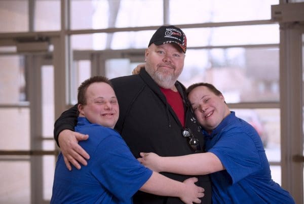 Twin brothers with Down Syndrome hug their father after a happy dentist and doctor appointment.