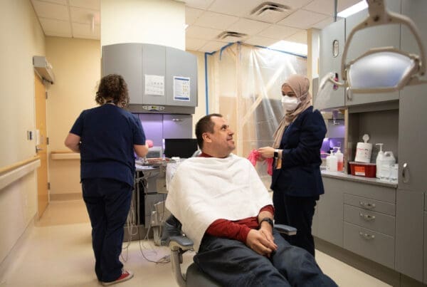 Neurodivergent patient smiles as Dentist and assistant adapt to create a sensory-friendly environment for the individual.