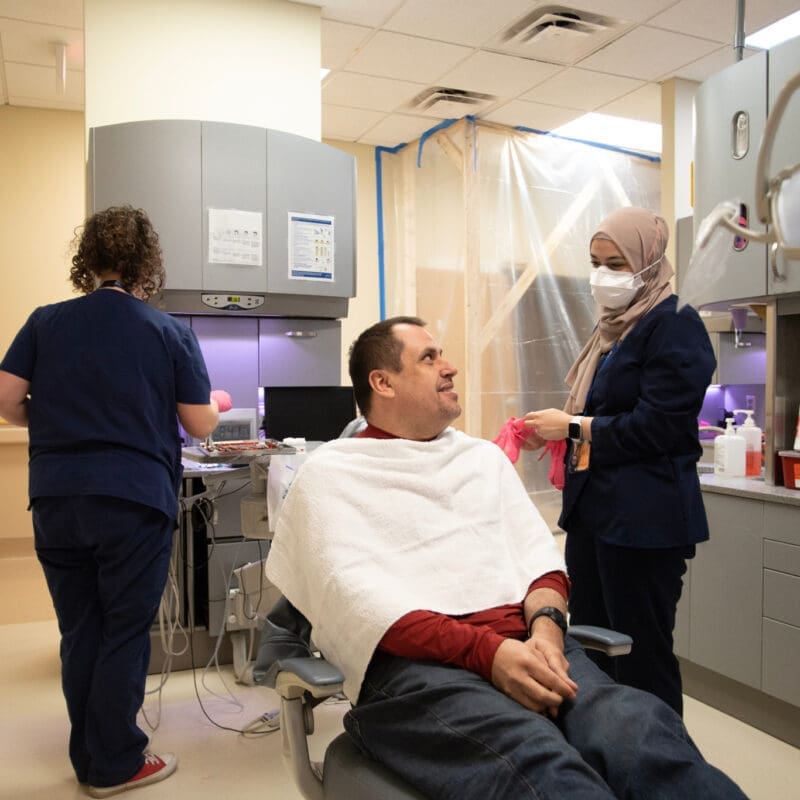 Neurodivergent patient smiles as Dentist and assistant adapt to create a sensory-friendly environment for the individual.