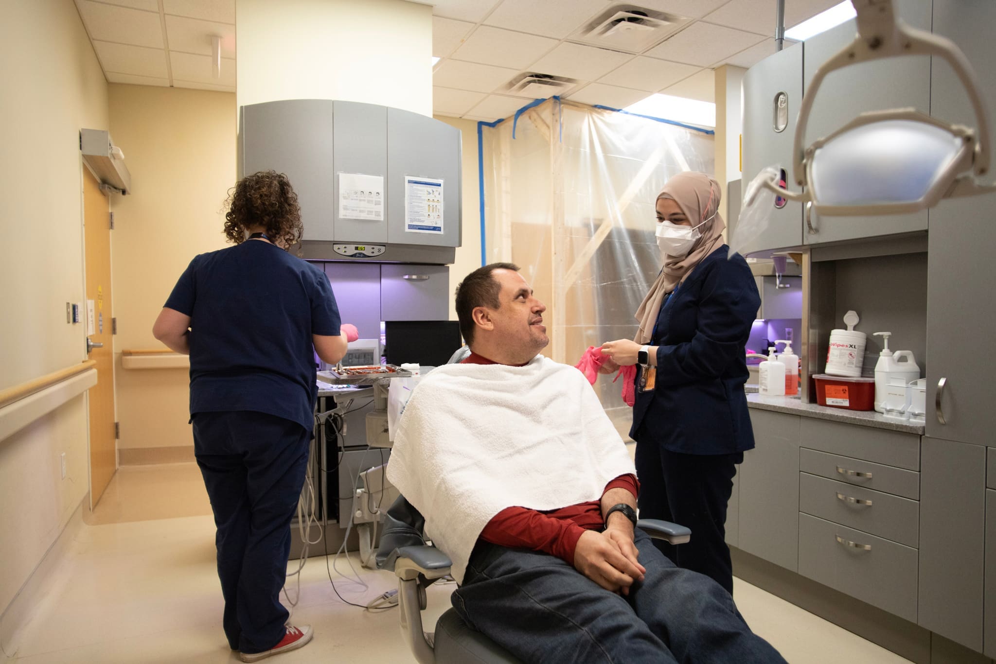 Neurodivergent patient smiles as Dentist and assistant adapt to create a sensory-friendly environment for the individual.